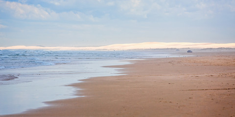 Coastal seascape with breaking waves, sand and sand dunes