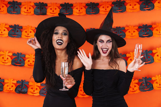 Image of witch women in halloween costume holding champagne glasses