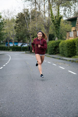 Young female athlete running at urban suburbs street road on autumn.