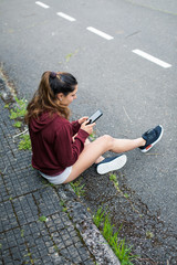 Sporty young woman taking a running rest for checking workout goals on smartphone app.