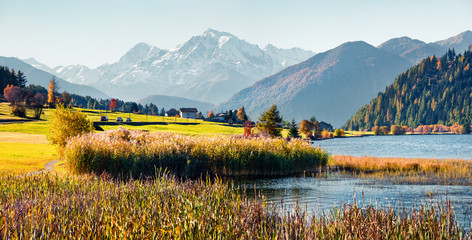 Panoramic autumn scene of Haidersee (Lago della Muta) lake with Ortler peak on background. Breathtaking morning view of Italian Alps, Italy, Europe.Beauty of nature concept background.