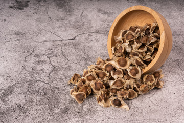 Moringa Oleifera seeds dried in a wooden bowl on the cement floor. Top food for health.