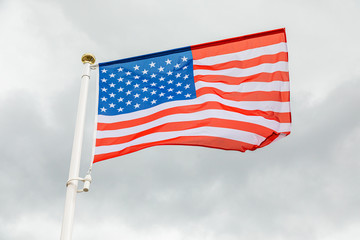 flag of the USA against white cloudy sky