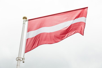 Fototapeta na wymiar Latvian flag waving in the wind against sky