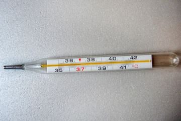 Thermometer for measuring body temperature in case of illness on a gray surface, photographed in close-up