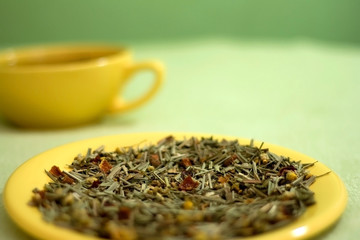 Tea leaves on a plate, cup of tea in the background. Selective focus.