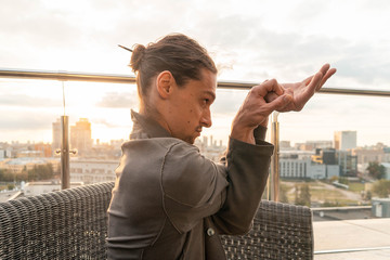 Attractive athletic man practicing yoga in business center with beautiful view on a city from skyscraper.