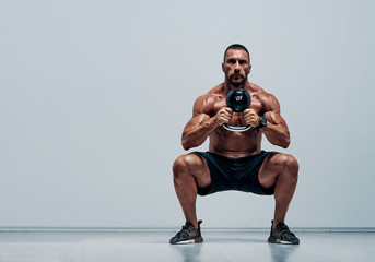 Handsome Muscular , Cross Training Athlete Doing Squats With Kettlebell