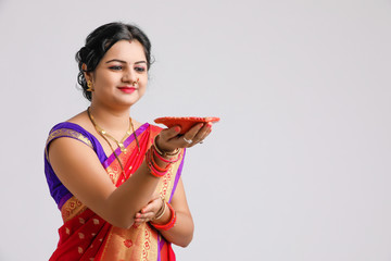 Indian woman in traditional sari and holding oil lamp in Hand celebrating Diwali or deepavali,...