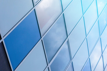 Close-up of glass wall surface with blue sky reflection.