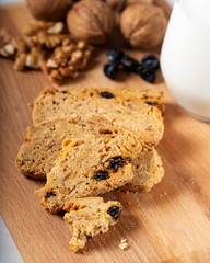 Crispy cookies with walnut and raisins. Glass of milk on wooden background.