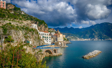 The seaside village of Atrani with mountains in the distance surrounded by turquoise blue water. One of the fairy villages, part of the Amalfi Coast (Costiera Amalfitana)