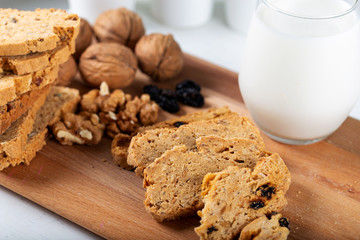 Crispy cookies with walnut and raisins. Glass of milk on wooden background.