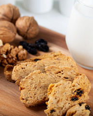 Crispy cookies with walnut and raisins. Glass of milk on wooden background.