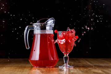 Cranberry juice in a jug on a wooden table.