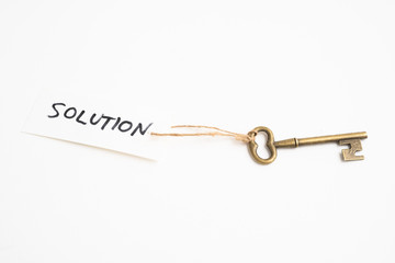 Old vintage brass key with solution word tag on white background