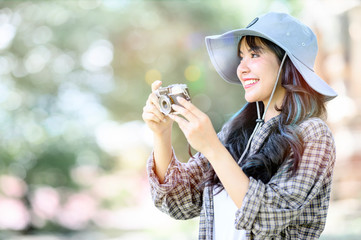 Portrait of young beautiful asian woman taking photo with vintage camera while standing outdoors.