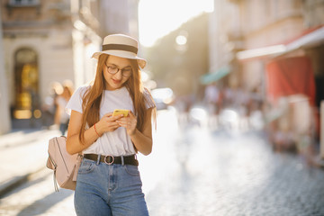 Young Woman Walking in the City. Using her Mobile Phone. Chatting on it. Typing a Message. Girl Looking Excited, Satisfied. Smiling Happily