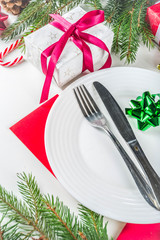 Christmas festive table setting with with a plate, fork, Christmas decorations, gift boxes, fir tree branches, glass and champagne bottle. Holiday table background copy space