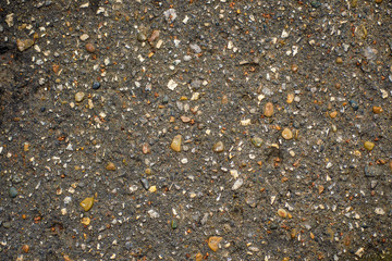 Texture of dry gray asphalt with pebbles and small stones. Concept of abstract rough scabrous surface. Minimalistic background design with copy space. Eclectic flat lay in loft style, gravel top view