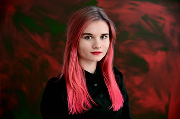Fototapeta premium Close-up portrait of a pretty girl with colored hair on a colorful background.