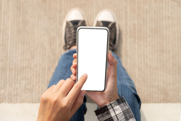 Woman hand holding and using mobile phone with blank screen sitting in the outdoor