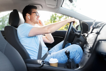transport, vehicle and people concept - smiling man or driver with wireless earphones driving car