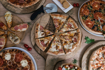 Italian pizza and pizzeria concept. Different pizza set for menu. Take away food with various ingredients and crunchy edge. Pizza circles with meat, mushrooms, tomatoes and cheese on wooden background