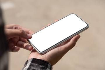 Woman hand holding and using mobile phone with blank screen sitting in the outdoor