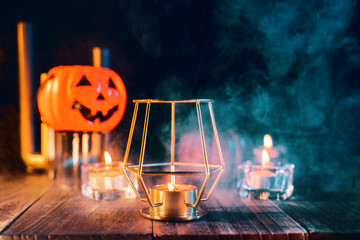 Halloween holiday concept design of pumpkin, candle, spooky decorations with green tone smoke around on a dark wooden table, close up shot.