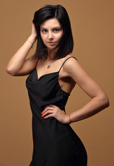 Obraz premium Slim girl in black dress on beige background