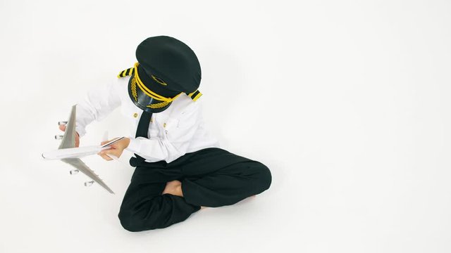 Boy in pilot's uniform playing with toy airliner