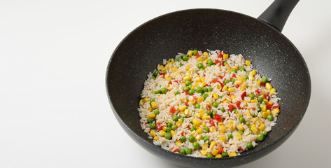 Pan of mix rice with sweet corn and fresh organic vegetables fried in sunflower oil with copy space. Rice, sweet corn, sweet red pepper, green pea. Healthy vegan diet foods.