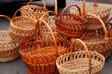 Group of empty wicker baskets for sale in a market place. Heap of wicker baskets dark brown oval round sale at the farmers market