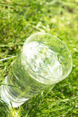 A glass of clean transparent drinking water on a grass background.