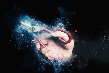 man hand holding big scissors on black background  - concept of cutting waste or human resources -...