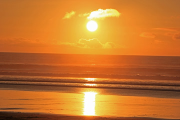 Fototapeta na wymiar orange and yellow sunset at muriwai beach