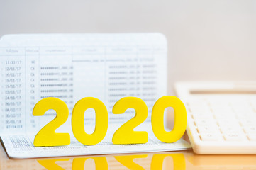 Wood block 2020 on bank passbook with calculator. Concept of income and budget planning for year 2020. Investment in business development for growth and success, dividend payment to investors.