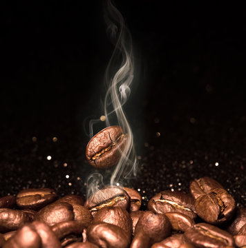 Roasted coffee beans. Seeds of freshly roasted coffee with smoke. Coffee beans closeup with emphasis on the grain with smoke. © ninell