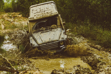 Mud and water splash in off the road racing. Tracks on a muddy field. Off-road vehicle goes on mountain way. Expedition offroader. Jeep crashed into a puddle and picked up a spray of dirt.
