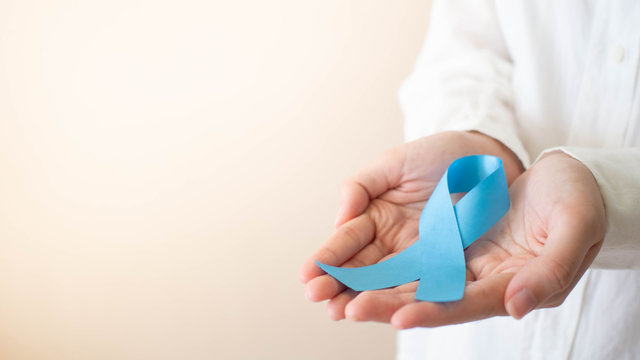 Men's health and Prostate cancer awareness campaign in November month. Close up of young man hands holding light blue ribbon awareness. Symbol for support men who living w/ cancer. Copy space.