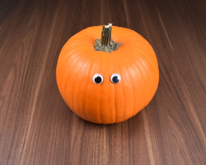 Halloween pumpkin with googly eyes stock images. Halloween pumpkin with googly eyes on a wooden background. Single cute halloween pumpkin on a dark background