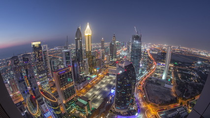 Obraz premium Skyline of the buildings of Sheikh Zayed Road and DIFC aerial day to night timelapse in Dubai, UAE.