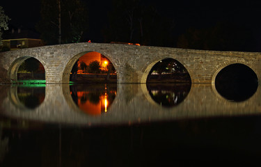 Old stone bridge and its reflection at night