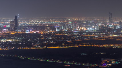 Aerial view to Creek and zabeel district night timelapse with traffic and under construction building with cranes from downtown