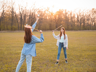 Naklejka na ściany i meble Two girls play badminton on the field at sunset