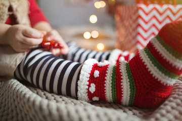 warm knitted socks close up on baby on background of gifts and Christmas lights