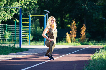 Beautiful young woman makes sport exercises on the sport ground, blurred background