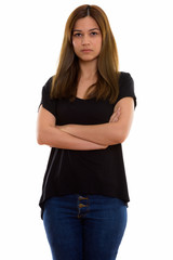 Studio shot of young beautiful woman standing with arms crossed