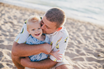 Father having fun with son on beach at sunset